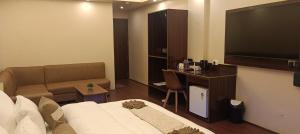 a hotel room with a bed and a flat screen tv at XCELSIOR HOTEL AND SPA by ROH in Shillong