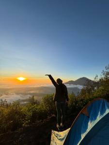 Eine Frau, die auf einem Hügel neben einem Zelt steht. in der Unterkunft Mount Batur camping in Kubupenlokan