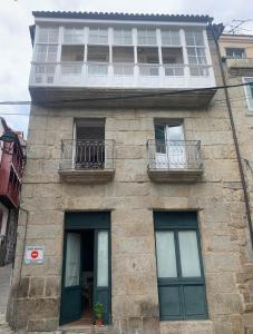 a stone building with two windows and a balcony at A Casa do Sastre1 in Ribadavia