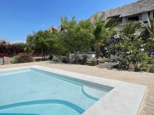 a swimming pool in front of a house at Charming Coastal Apartment in Watamu