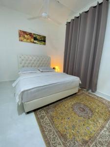 a bedroom with a bed and a rug and curtains at Golf Avenue Homestay Kota Bharu in Pengkalan Cepa