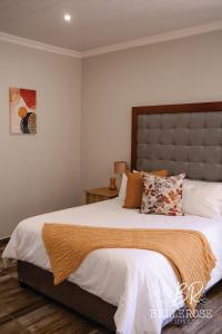 a bedroom with a large bed with white sheets and pillows at Bellerose Guesthouse in Klerksdorp +82 photos