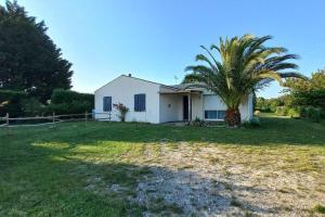 a house with a palm tree in the yard at Maison à la campagne in Meursac