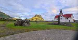 a church with rocks in front of a mountain at Bjarg Apartments in Grundarfjordur