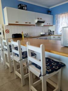 a kitchen with white cabinets and a wooden table with chairs at Point Village Accommodation - Galathea 6 in Mossel Bay +14 photos