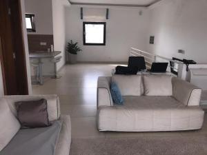 Keur Ndiaye LôCheerful flat with terrace in contemporary duplex with trees and garden的客厅配有白色沙发和两台笔记本电脑