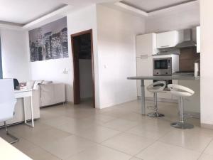 Keur Ndiaye LôCheerful flat with terrace in contemporary duplex with trees and garden的白色的厨房配有一张桌子和两张凳子