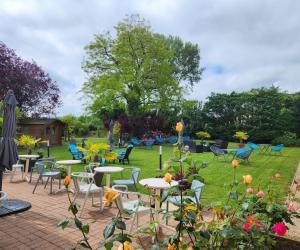 a group of tables and chairs in a garden at Hôtel Nell Axelle - Maison Tassoni in Saint-Marcel