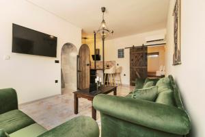 a living room with two green couches and a tv at Mailo&Luke apartments in Rhodes Town
