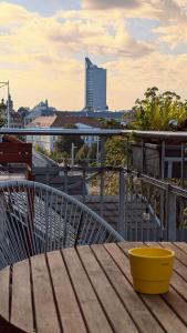 a wooden table on a balcony with a yellow bowl at Großzügige Maisonette über dem Leipziger Zentrum in Leipzig
