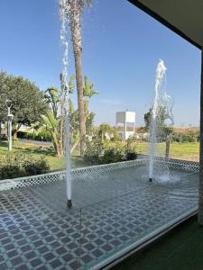 a water fountain in a park with a palm tree at Super belle villa avec piscine in Fès