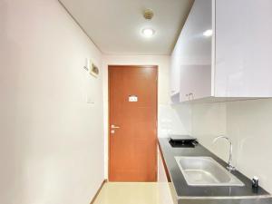 a kitchen with a sink and a brown door at Good Choice Studio Room at Gateway Pasteur Apartment By Travelio in Bandung