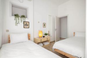 a white bedroom with two beds and a table at Ben Yehuda Elegant City Retreat with Shelter by Sea N Rent in Tel Aviv