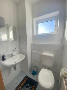 a white bathroom with a toilet and a sink at Pension 28 - Zimmer 1-3 in Velgast