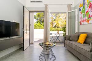 a living room with a couch and a television at Theo's Cozy Apartment's near Athens airport in Spáta