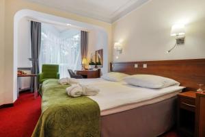 Pokój hotelowy z dużym łóżkiem i zielonym krzesłem w obiekcie Papuga Park Hotel Wellness Marrakesz & SPA w Bielsku Białej