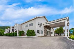 a large white building with a parking lot at Quality Inn & Suites Gorham Riverside in Gorham