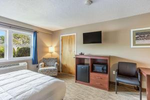 a bedroom with a bed and a tv and a desk at Quality Inn & Suites Gorham Riverside in Gorham