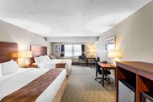 a hotel room with two beds and a desk at Quality Inn & Suites Gorham Riverside in Gorham