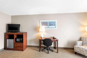 a hotel room with a desk and a tv and a chair at Quality Inn & Suites Gorham Riverside in Gorham