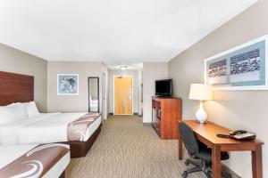 a hotel room with a bed and a desk with a computer at Quality Inn & Suites Gorham Riverside in Gorham