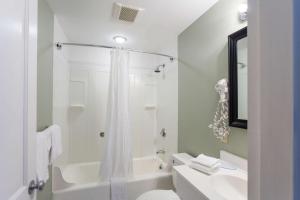 a white bathroom with a tub and a toilet and a sink at Quality Inn & Suites Gorham Riverside in Gorham