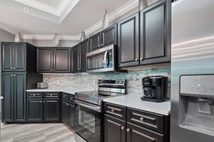 a kitchen with black cabinets and white counter tops at Phoenix on the Bay 1-1114 in Orange Beach