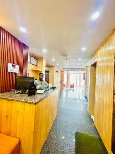 a man sitting at a counter in a room at Hotel Asraya in Kanatal