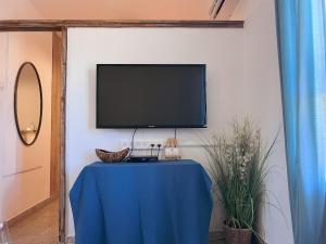 a tv on a wall with a table with a blue table cloth at הצימר של יהושע in Ein Gedi