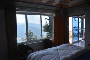 Un dormitorio con una cama y una ventana grande. en Mountain View Guest House by LMC, en Nathia Gali