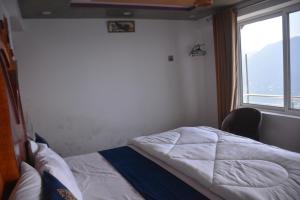 una cama en una habitación con una ventana grande en Mountain View Guest House by LMC, en Nathia Gali