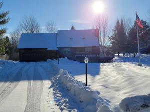 une maison est recouverte de neige avec une clôture dans l'établissement Adirondack Cozy Cottage Hideaway home, à Olmstedville