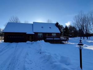 une maison recouverte de neige à côté d'un pôle lumineux dans l'établissement Adirondack Cozy Cottage Hideaway home, à Olmstedville 39 autres photos