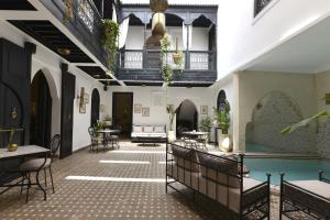 um quarto com piscina, mesas e cadeiras em Riad Zoraida em Marraquexe