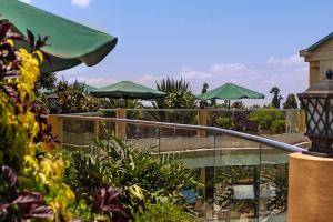 a patio with tables and green umbrellas and plants at Roswam Hotel in Keruguya