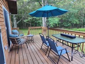 Rustic Catskills Cabin with Hot Tub and Mountain Views في Prattsville: فناء مع طاولة وكراسي ومظلة