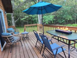 Rustic Catskills Cabin with Hot Tub and Mountain Views في Prattsville: فناء مع طاولة وكراسي ومظلة