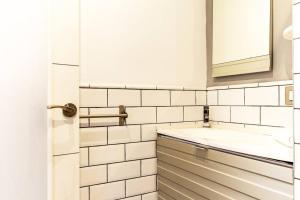 a white tiled bathroom with a sink and a mirror at Apartamento con terraza privada cerca de la playa in Valencia +13 photos