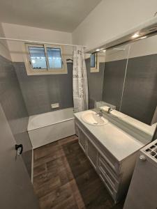 a bathroom with a sink and a tub and a mirror at Appartement GGCH 4 chambres in Montélimar