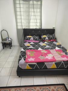 a bedroom with a black bed with a pink blanket at Momies house in Ipoh