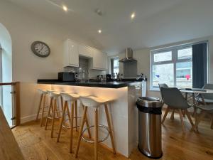 a kitchen with bar stools and a clock on the wall at The Old Bakery in Fowey