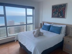 a bedroom with a bed with blue pillows and a window at Ocean View B1001, Blouberg in Bloubergstrand