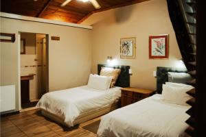 a bedroom with two beds and a bathroom at The Grey's Inn in Machadodorp