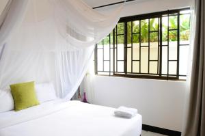 a bedroom with a white bed and a window at OYA Guest House in Usa River