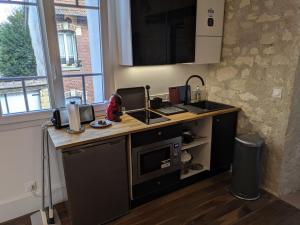 a kitchen with a counter with a sink and a microwave at 2 Pièces Neuf Centre Ville, Magny Compiègne in Margny-lès-Compiègne
