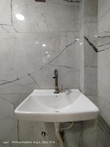a white sink in a bathroom with marble walls at junagadh places in Ujjain