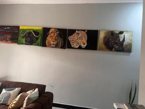 four pictures of animals on a wall above a couch at Sinana Escapes - Arusha in Arusha +36 photos