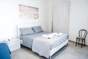 a white bedroom with a bed and a chair at Bed & Breakfast Terra d'Arneo in Leverano
