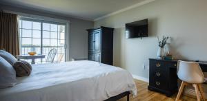 a bedroom with a bed and a dresser and a television at Malia Spa and Resort inc in Lamèque