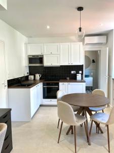 マントンにあるStudio de charme proche gareの白いキャビネットとテーブルと椅子のあるキッチン